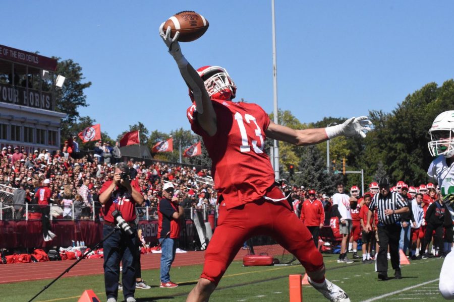 
Varsity Football player Braden Contreras, sporting the number 13 on his jersey, is captured in this action shot at Hinsdale Central’s football stadium. The Junior, who has been playing football during his last three years his high school career, is snatching the football with a one handed catch as his teammates, schoolmates and supporters watch. 
