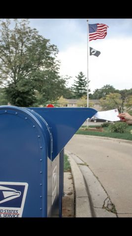 A person putting their mail in ballot for the election in their mailbox.