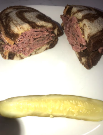 Schmaltz Delis Hot Pastrami sandwich with a side of a dill pickle. Each item is made with love, and probably a reoccurring sound of Bubbies voice telling them to work harder.