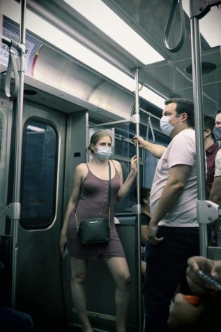 A masked woman stands in a crowded train on the red line towards Chicago.