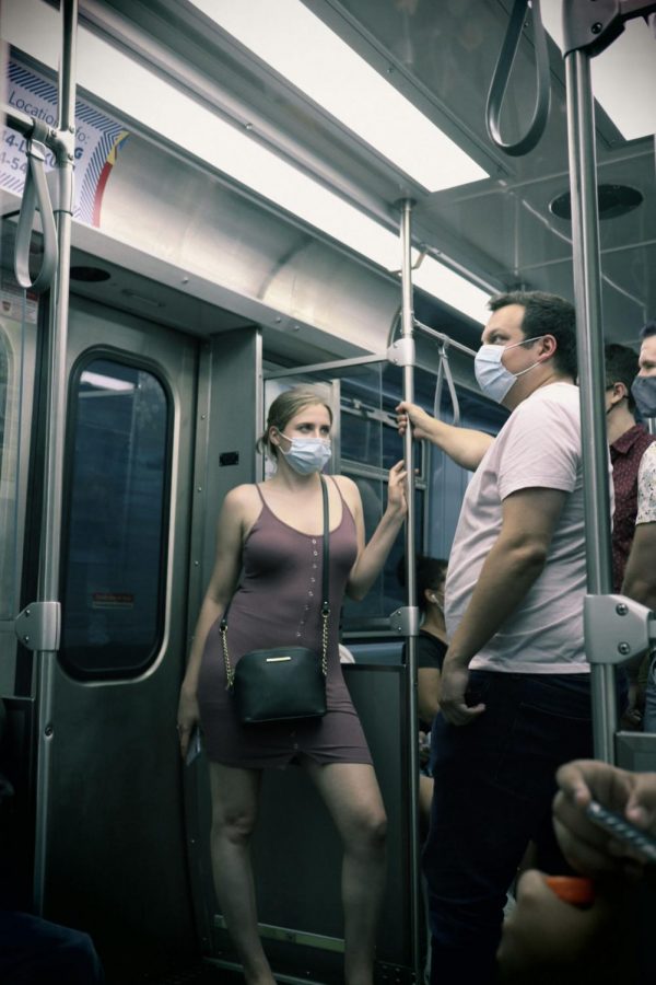 A+masked+woman+stands+in+a+crowded+train+on+the+red+line+towards+Chicago.