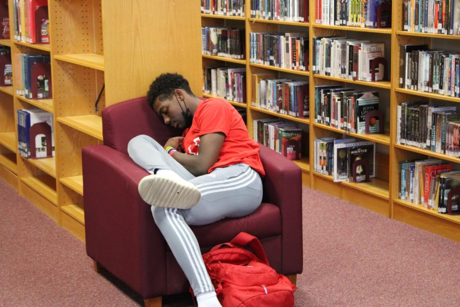 A student sleeps in the library after a tiring day.