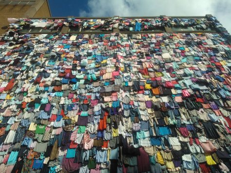 Clothes hang on a wall. The impacts of fast fashion are immense, even if we dont see them directly.