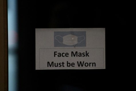 A local sign shows a message to require people to wear face masks in the building. 
