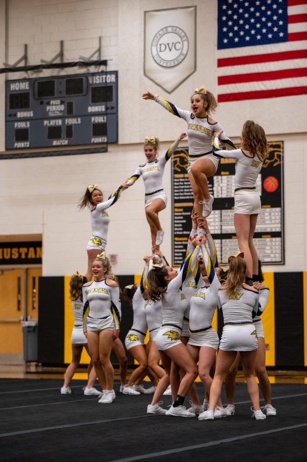 Cheerleaders perform stunts by lifting and supporting while the flyer gets thrown up in the air.