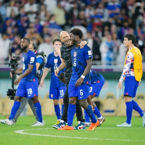 USMNT coach Gregg Berhalter embraces midfielder Yunus Musah in celebration of their 1-0 victory over Iran.